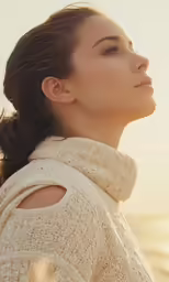 a woman with brown hair standing in front of a lake