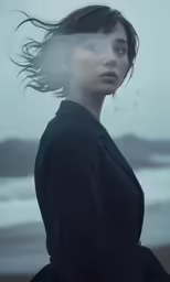 a woman is standing in the rain wearing a black coat
