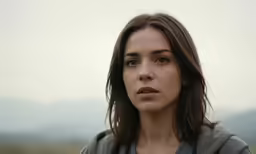 a young girl in a hoodie looks off to her right