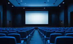 an empty auditorium with rows of chairs facing the large screen