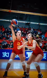 two female volleyball players trying to make contact with a ball