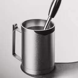 a cup on top of a metal table with a spoon inside