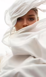 a woman under a white blanket with her head covered