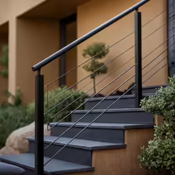 some stairs and handrails with plants near a building
