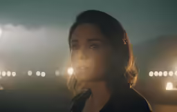 a woman looking at the camera in front of the night sky