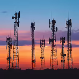 multiple cell towers against an orange and blue sky