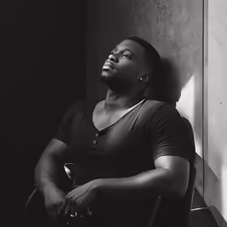 an african american man is sitting in a chair and looks off into the distance