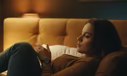 the woman is sitting on the sofa holding her cigarette
