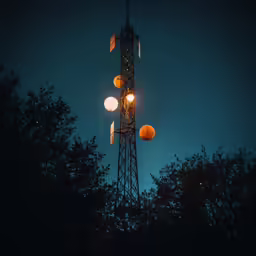 several different street lights and a tall structure in the evening