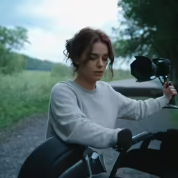 a woman riding a motorcycle next to a field