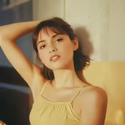 a young woman sitting on a yellow couch wearing a tank top