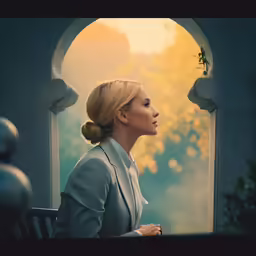 a woman wearing a gray suit sitting in an archway