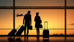 two people in front of a window with luggage in front of them,two people who are standing near some suitcases