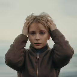 a boy is covering his ears with his hands