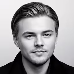 the young man looks at the camera while wearing a black jacket