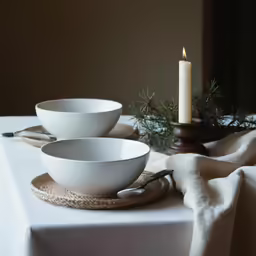 there are bowls sitting on the table with a lit candle