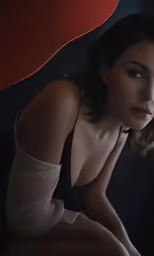 a woman sitting on top of a red chair in a dark room