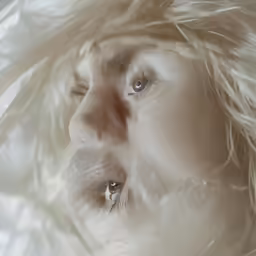 the beautiful blonde is laying under a white blanket
