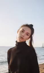 a young lady posing by the sea in her black sweater