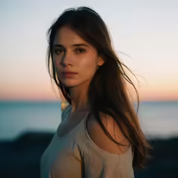 an attractive young lady standing near the ocean