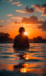silhouette of man sitting in water with beautiful sunset