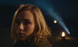 a blonde woman stands near a streetlight in the dark