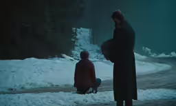 a man and a child walking through snow covered ground