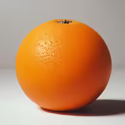 an orange is on a white surface next to a white wall