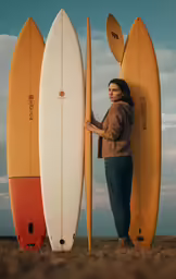 a woman holding two surfboards in front of two surf boards