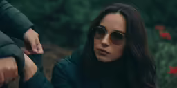 woman with dark hair and sunglasses looking at something off camera