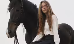 woman with long hair riding on the back of a horse