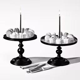 two cakes are placed on two pedestals with two candles
