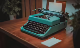 a close up of a blue old fashioned typewriter on a desk