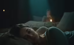 a woman laying down on top of a bed in a dark room