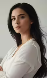 a woman in a white shirt leaning up against a wall