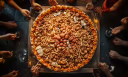 people standing around a pizza with some cut out pieces of meat on it