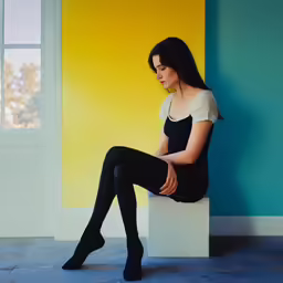 woman with long hair wearing black and white sitting on the ledge