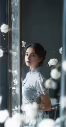 woman standing in front of a window with petals falling from it