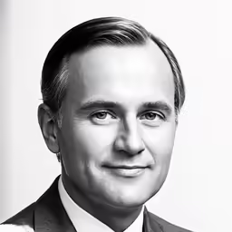 black and white photograph of man in suit smiling at camera