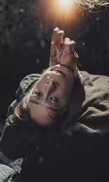 a woman with painted hands on her face is lying down