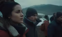 three people wearing winter hats and clothing near water