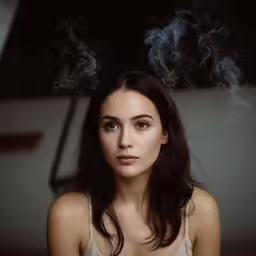 a beautiful young woman sitting down smoking a cigarette