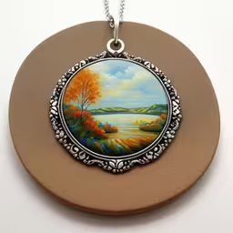 there is an orange tree on the painting,a round painting on a wall in the shape of a medallion,a close up of a plate with a picture on it,there is a small photo on a circle,this is a picture of a pendant with a beautiful landscape on it