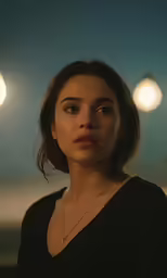 woman standing in front of lights with one eye opened