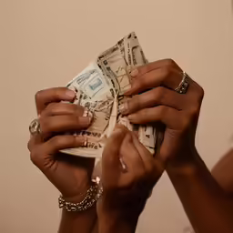 a couple of women holding onto a stack of paper money