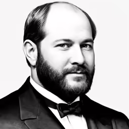a bearded man in a tuxedo looking at the camera