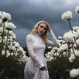 a woman in a white dress walking amongst flowers