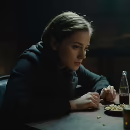 a woman sits at a table while eating