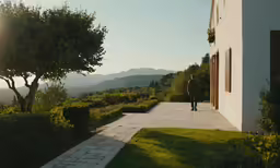 man walking towards door way in front of building and mountains