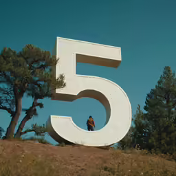 a sculpture of a man at the top of a hill with numbers in the foreground